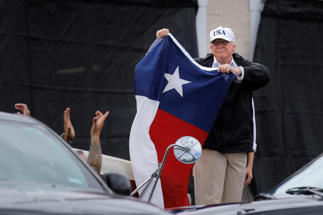 Đ&acirc;y l&agrave; chuyến thị s&aacute;t đầu ti&ecirc;n của Tổng thống Trump tới Texas từ sau khi cơn b&atilde;o Harvey, cơn b&atilde;o được đ&aacute;nh gi&aacute; l&agrave; mạnh nhất trong v&ograve;ng 50 năm qua, đổ bộ v&agrave;o khu vực n&agrave;y. &Ocirc;ng Trump đ&atilde; gặp gỡ c&aacute;c l&atilde;nh đạo địa phương v&agrave; người d&acirc;n để nghe b&aacute;o c&aacute;o về t&igrave;nh h&igrave;nh thi&ecirc;n tai. Trong ảnh: Tổng thống Trump cầm cờ của bang Texas gặp gỡ người d&acirc;n ở Corpus Christi. (Ảnh: Reuters)