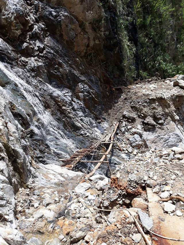 Một đoạn đường bị sạt lở phải bắc cầu tạm l&agrave; những thanh gỗ, c&acirc;y rừng để băng qua.