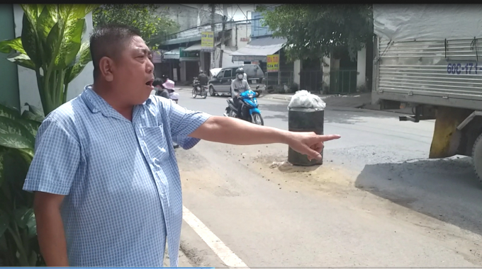 Ông trường chỉ tay về con đường vừa được sửa trước đây là vũng lớn khiến ông phải đặt thùng phuy để đảm bảo an toàn cho người lưu thông.