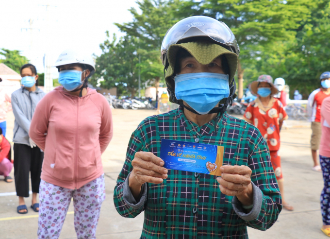 Bà Nguyễn Thị Hiền vui mừng cầm tấm vé để mua nhu yếu phẩm cho mình và con gái