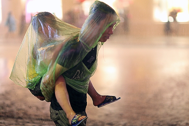 Nhiều trẻ em được cha mẹ cho đi tham gia phố đi bộ dầm m&igrave;nh trong cơn mưa lớn.