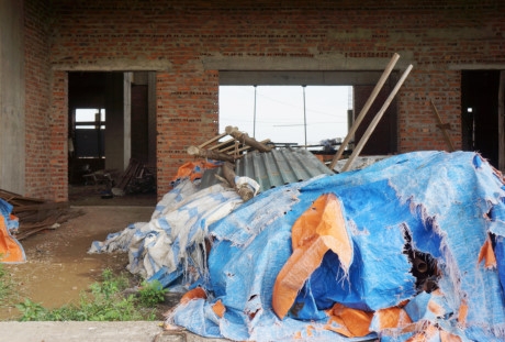 B&ecirc;n trong tầng 1 căn nh&agrave; 9 tầng c&oacute; nhiều đồ đạc, vật liệu x&acirc;y dựng phủ bạt,