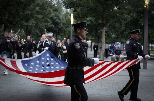 S&aacute;ng sớm 11/9/2015, th&agrave;nh vi&ecirc;n lực lượng cảnh s&aacute;t New York rước quốc kỳ Mỹ tại khu tưởng niệm c&aacute;c nạn nh&acirc;n vụ tấn c&ocirc;ng khủng bố 11/9/2001. (Ảnh: AFP)