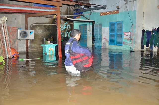Một c&ocirc;ng nh&acirc;n phải gom đồ ra ngo&agrave;i v&igrave; ph&ograve;ng đ&atilde; bị ngập s&acirc;u.
