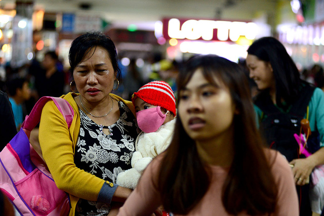 Một em b&eacute; mệt mỏi tựa l&ecirc;n vai mẹ đi kiếm v&eacute; về qu&ecirc;.