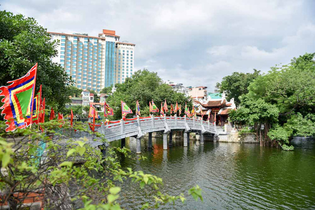 Đền được nối với bờ bằng c&acirc;y cầu đ&aacute; bắc qua mặt hồ Tr&uacute;c Bạch. Cầu d&agrave;i 18m gồm năm nhịp, mỗi nhịp d&agrave;i 3,6m, rộng 2,25m.  Theo một t&iacute;ch xưa truyền lại, nơi đ&acirc;y từng c&oacute; một di t&iacute;ch do vua L&yacute; C&ocirc;ng Uẩn cho x&acirc;y để thờ cặp ch&oacute; mẹ - ch&oacute; con th&agrave;nh thần. Ch&oacute; con khi sinh ra, tr&ecirc;n l&ocirc;ng c&oacute; những đốm gh&eacute;p lại th&agrave;nh chữ