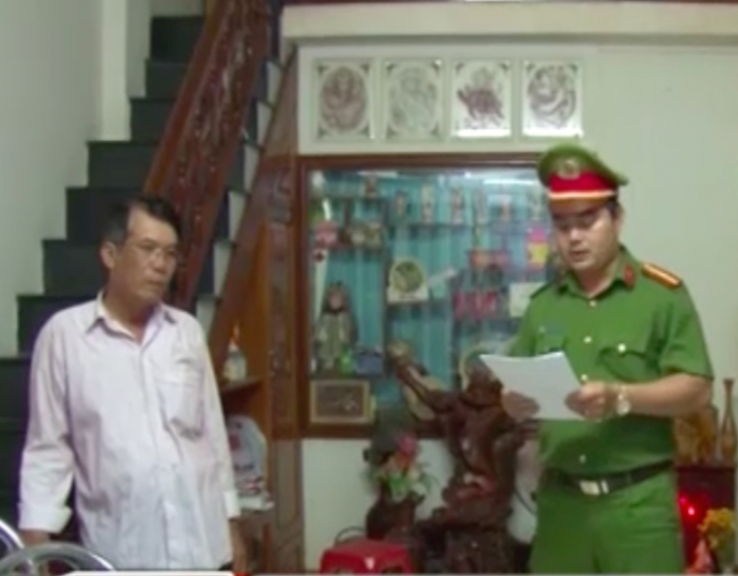 Trương C&ocirc;ng Lộc, kế to&aacute;n TAND tỉnh Ph&uacute; Y&ecirc;n (b&igrave;a tr&aacute;i) nghe đại diện cơ quan C&ocirc;ng an đọc Quyết định&nbsp;khởi tố bắt tạm giam về h&agrave;nh vi tham &ocirc; t&agrave;i sản.