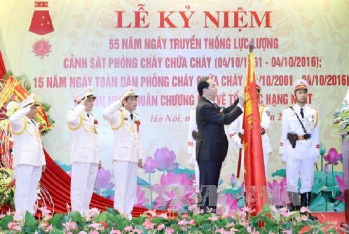 Chủ tịch nước Trần Đại Quang trao Hu&acirc;n chương Bảo vệ Tổ quốc hạng Nhất tặng Cục Cảnh s&aacute;t ph&ograve;ng ch&aacute;y chữa ch&aacute;y. Ảnh: Nhan S&aacute;ng/TTXVN.