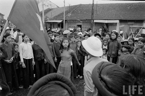 Nh&acirc;n d&acirc;n khắp nơi đủ mọi lứa tuổi &ugrave;a ra đường cầm l&aacute; cờ đỏ sao v&agrave;ng v&agrave; h&aacute;t b&agrave;i