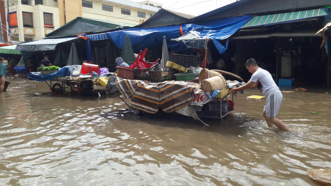 C&aacute;c tiểu thương b&igrave; b&otilde;m đẩy h&agrave;ng ra khỏi khu vực bị ngập để bu&ocirc;n b&aacute;n.