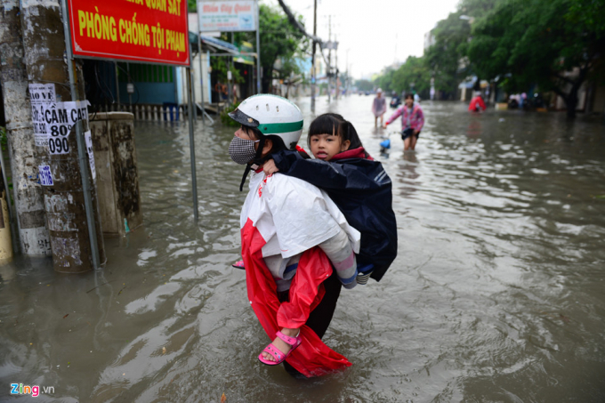 Một trong những phụ huynh kh&aacute;c vất vả lội nước đưa con đi học tr&ecirc;n đường An Dương Vương, quận 6.