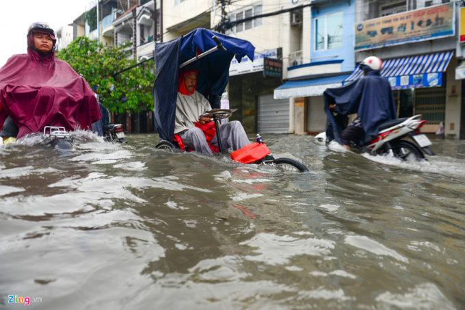 Trong khi đ&oacute;, một người đ&agrave;n &ocirc;ng ngồi xe đạp 3 b&aacute;nh cố vượt qua đoạn ngập tr&ecirc;n đường Phan Anh&nbsp;(quận 6) để b&aacute;n v&eacute; số.