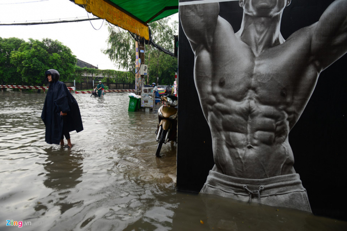 Lo ngại sẽ bị sụp hố giữa đường ngập nước, người đ&agrave;n &ocirc;ng dắt xe dựng s&aacute;t nh&agrave; d&acirc;n chờ nước r&uacute;t để đi tiếp.