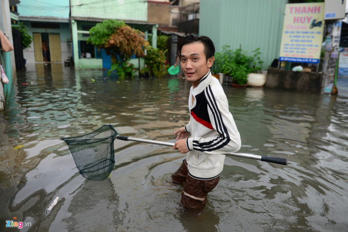 Trong l&uacute;c đ&oacute;, người d&acirc;n tranh thủ ra đường bắt c&aacute; giữa d&ograve;ng nước ngập.