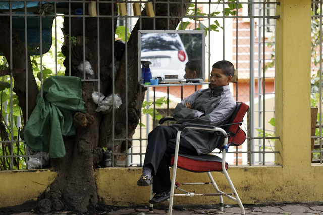 Người cắt t&oacute;c ngồi co ro đợi kh&aacute;ch.