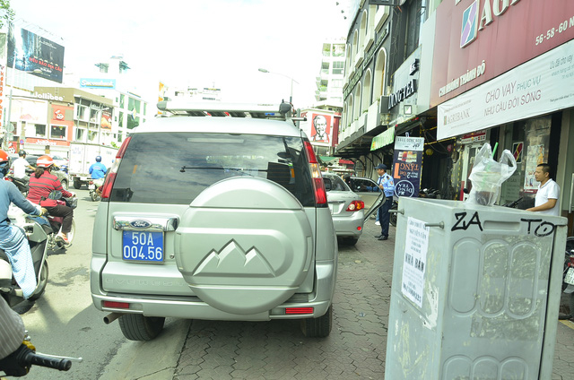 Xe c&ocirc;ng an v&agrave; xe biển xanh cũng đậu chiếm hết vỉa h&egrave; của người đi bộ.