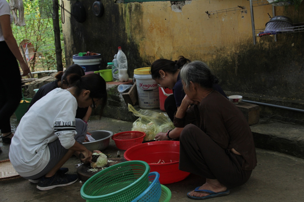 Cụ Nguyễn Thị Sợi (bệnh nh&acirc;n phong), ngồi xem c&aacute;c bạn t&igrave;nh nguyện vi&ecirc;n chuẩn bị đồ để nấu cơm.