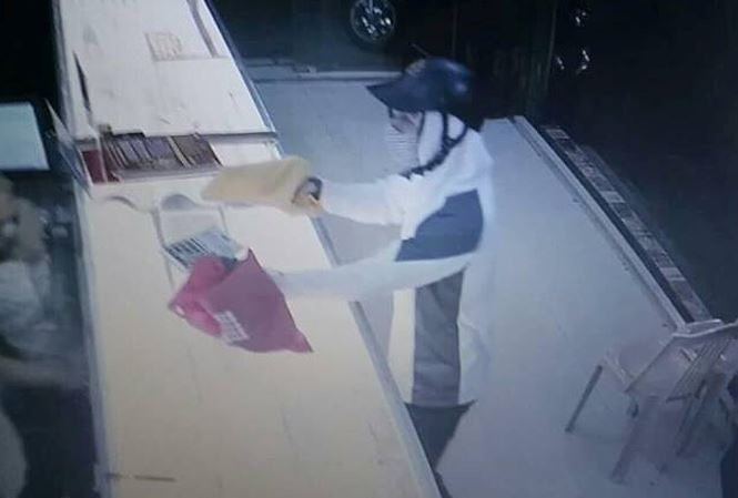 T&ecirc;n cướp giơ vật gống khẩu s&uacute;ng được giấu trong chiếc t&uacute;i m&agrave;u v&agrave;ng (Ảnh cắt từ video).