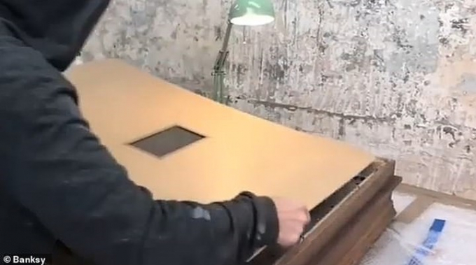 Banksy được cho l&agrave; đeo chiếc mặt nạ m&agrave;u đen khi lắp thiết bị n&agrave;y v&agrave;o sau bức tranh. Ảnh: Banksy.