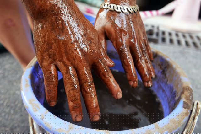 Cận cảnh xô nước cặn đáy bể được múc lên mặt đất đầy dầu thải.