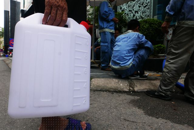 Người dân của tòa nhà cầm can đứng đợi lấy nước sạch để sinh hoạt, trong khi việc thau dọn bể chưa biết khi nào mới hoàn thành.