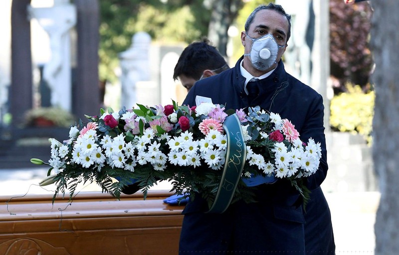 Nhân viên nhà tang lễ tiễn biệt nạn nhân nhiễm virus SARS-CoV-2 vào một nghĩa trang ở Bergamo, Italia. (Ảnh Reuters) 