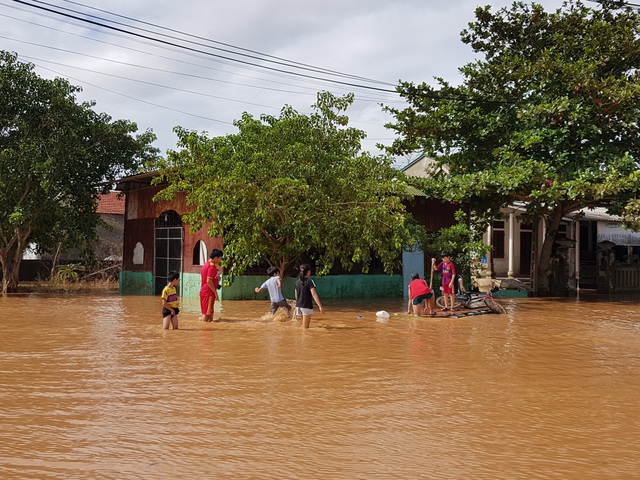 Các em nhỏ vui chơi trên con đường ngập nước.