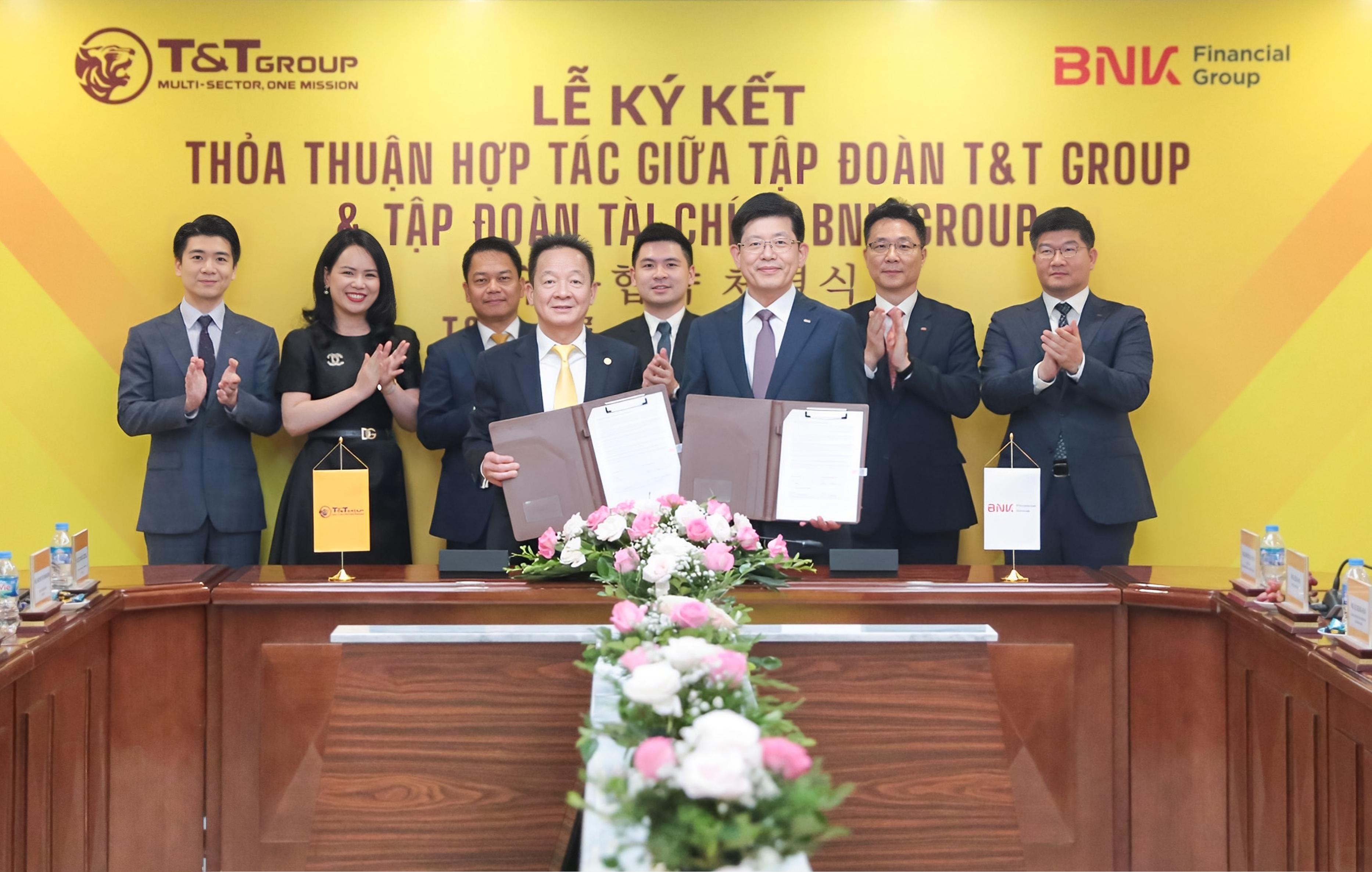 Ông Đỗ Quang Hiển, Chủ tịch UBCL Tập đoàn T&amp;amp;T Group (bên trái) và ông Bin Dae-in, Chủ tịch HĐQT kiêm TGĐ Tập đoàn Tài chính BNK (bên phải) trao thỏa thuận hợp tác với sự chứng kiến của đại diện lãnh đạo hai Tập đoàn.