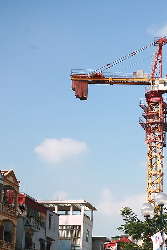 Một chiếc cẩu th&aacute;p c&oacute; khối b&ecirc; t&ocirc;ng đối trọng nằm lơ lửng tr&ecirc;n đầu nh&agrave; d&acirc;n