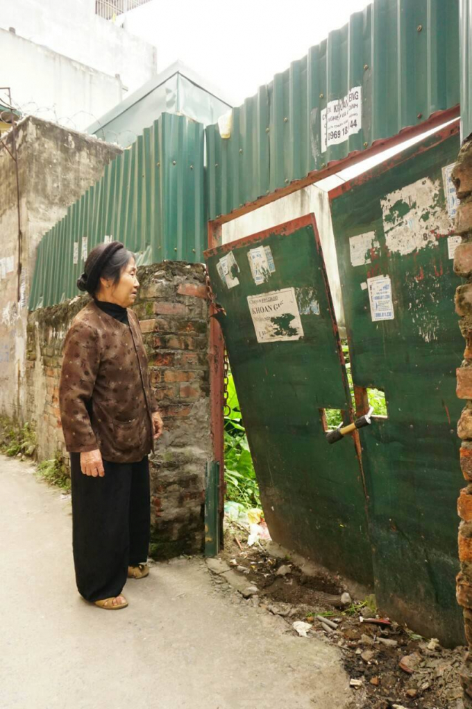 B&agrave; Lưu Thị Dong đứng trước khu vườn bị chặt ph&aacute; v&agrave; đang bị c&ocirc; Bưởi đ&oacute;ng cửa lại.