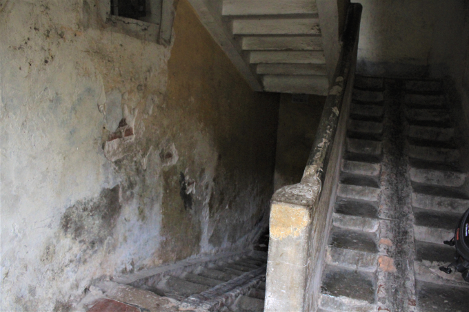 Cầu thang loang lổ những mảng tường nứt vỡ, trơ gạch.