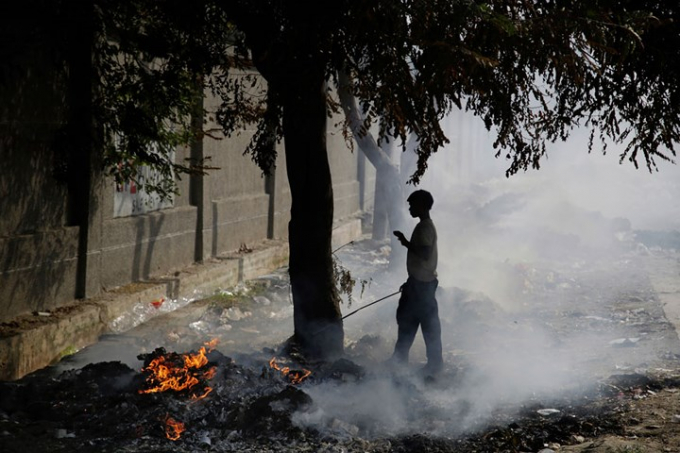 Một cậu b&eacute; đứng đốt r&aacute;c ở ngoại &ocirc; New Delhi. Ảnh: AP