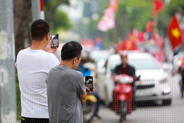 Người dân hai bên đường ghi lại hình ảnh của đoàn cổ động viên đang diễu hành.
