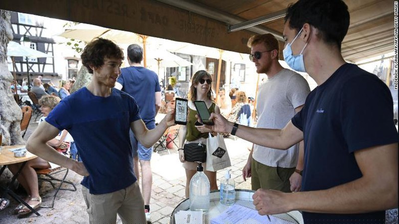 Một người phục vụ kiểm tra thẻ sức khỏe COVID-19 của một khách hàng ở Pháp. Ảnh: CNN
