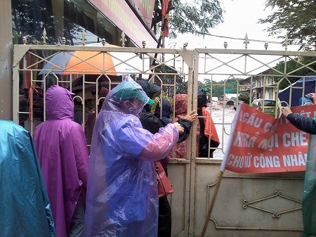 Những c&ocirc;ng nh&acirc;n b&ecirc;n trong v&agrave; b&ecirc;n ngo&agrave;i bị ngăn c&aacute;ch bởi c&aacute;nh cổng do C&ocirc;ng ty Dệt kh&oacute;a.