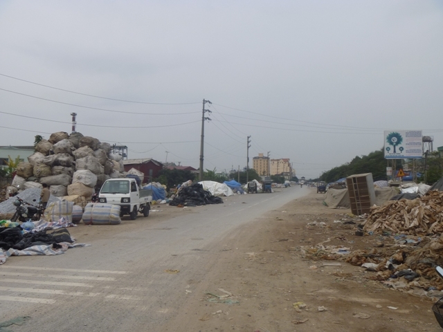 Rác được chất thành đống, nằm rải rác ven con đường dẫn vào làng