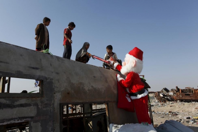 Những t&igrave;nh nguyện vi&ecirc;n đ&oacute;ng giả th&agrave;nh &ocirc;ng gi&agrave; Noel đi tặng qu&agrave; Gi&aacute;ng sinh cho trẻ em ở khu ngụ cư gần thủ đ&ocirc; Baghdad. (Ảnh: Reuters)