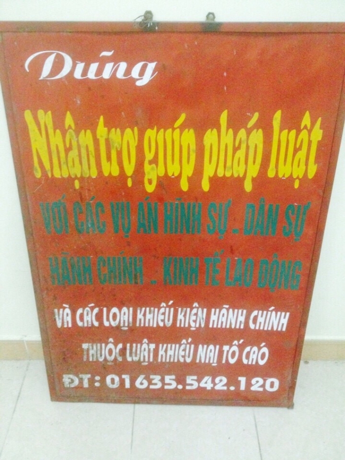 Dũng trưng tấm biển quảng c&aacute;o nhận trợ gi&uacute;p ph&aacute;p l&yacute; đặt trước cửa h&agrave;ng b&aacute;n thịt lợn.