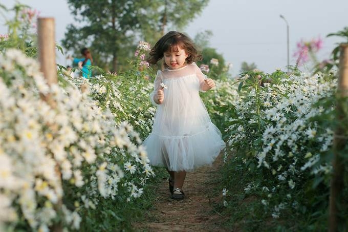 Thi&ecirc;n thần b&eacute; nhỏ vui đ&ugrave;a b&ecirc;n những luống hoa.