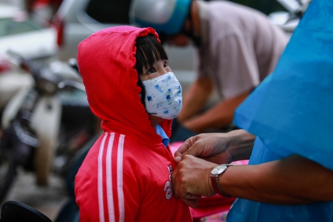 Một phụ huynh mặc &aacute;o kho&aacute;c cho b&eacute; g&aacute;i trong tiết trời se lạnh trước cổng Trường tiểu học Đinh Ti&ecirc;n Ho&agrave;ng, quận 1. Phụ huynh n&agrave;y cho biết, tiết trời cả ng&agrave;y vừa mưa, vừa lạnh n&ecirc;n trước khi đưa đ&oacute;n ch&aacute;u đ&atilde; chuẩn bị đầy đủ khẩu trang v&agrave; &aacute;o kho&aacute;c chống lạnh.