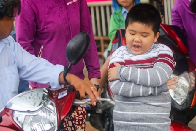 Trước cổng trường tiểu học Trần Quốc Tuấn (Quận T&acirc;n B&igrave;nh), cậu b&eacute; mặc &aacute;o len ấm &aacute;p, ngoan ngo&atilde;n khoanh tay ch&agrave;o bố khi v&agrave;o lớp học.