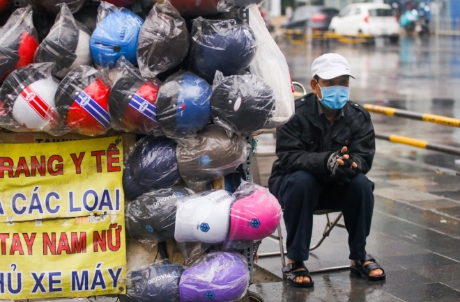 Kh&ocirc;ng kh&iacute; lạnh khiến người d&acirc;n ra đường cũng phải mặc &aacute;o ấm. H&igrave;nh ảnh tr&ecirc;n đường Cộng H&ograve;a, người b&aacute;n mũ bảo hiểm co ro trong thời tiết se lạnh.