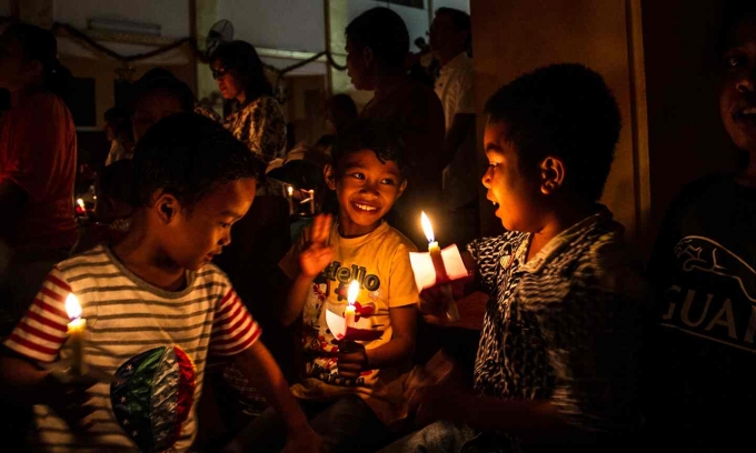 Trẻ em cầm nến tr&ecirc;n tay tại nh&agrave; thờ Hati Kudus, Indonesia trước thời khắc đ&ecirc;m Gi&aacute;ng sinh. (Ảnh: Albert Damanik / Barcroft)