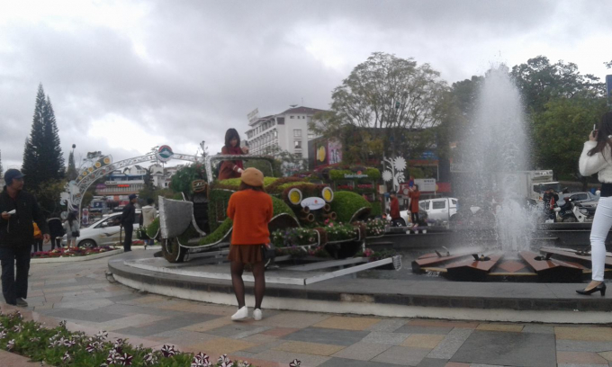 Du kh&aacute;ch chụp h&igrave;nh b&ecirc;n chiếc xe cổ gắn h&agrave;ng ng&agrave;n b&ocirc;ng hoa ở b&ugrave;ng binh phun nước nghệ thuật.