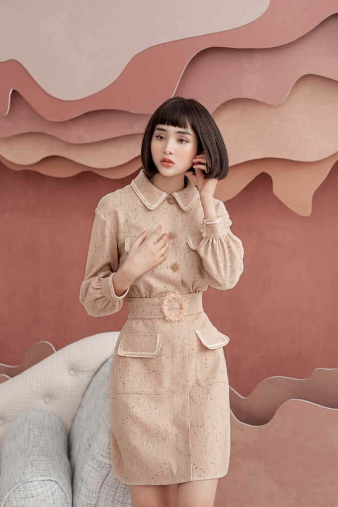 Hiền Hồ gợi &yacute; một thiết kế k&iacute;n đ&aacute;o với gam m&agrave;u be nh&atilde; nhặn, ph&ugrave; hợp c&aacute;c chị em c&ocirc;ng sở. Điểm nhấn nằm ở những chiếc khuy được đ&iacute;nh thủ c&ocirc;ng bằng đ&aacute;, ngọc trai v&agrave; phần đai lưng to bản.