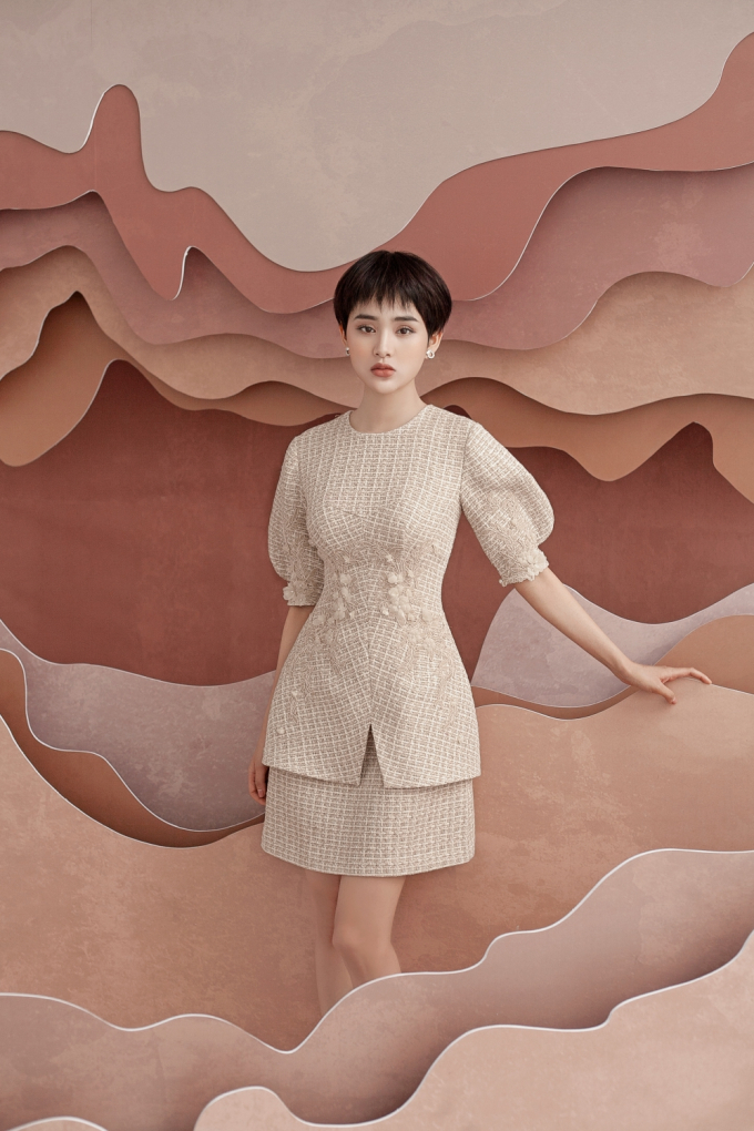 Chiếc đầm cổ tr&ograve;n, tay phồng cổ điển h&uacute;t mắt hơn nhờ phần ch&acirc;n v&aacute;y được c&aacute;ch điệu v&agrave; xếp lớp. Nh&agrave; mốt chọn họa tiết ren kết hợp hoa vải điểm xuyến nơi tay &aacute;o, eo v&aacute;y mang đến cảm gi&aacute;c thon gọn cho ngoại h&igrave;nh.