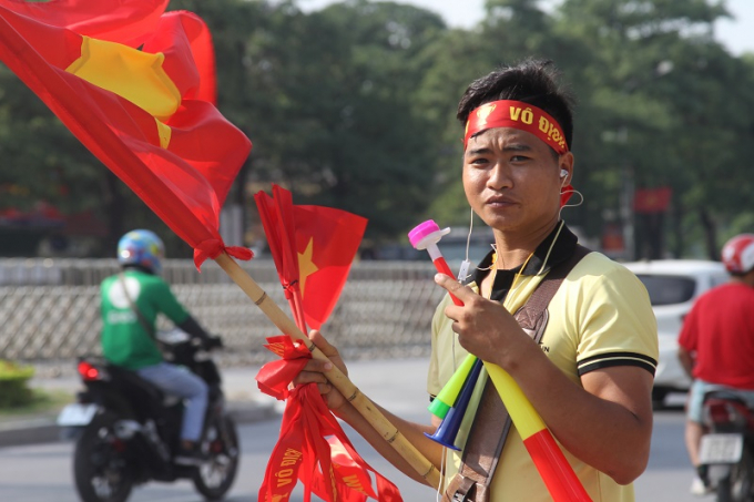 Một nam thanh ni&ecirc;n nhiệt t&iacute;nh mời kh&aacute;ch mua cờ, k&egrave;n cổ vụ cho đội tuyển Việt Nam.