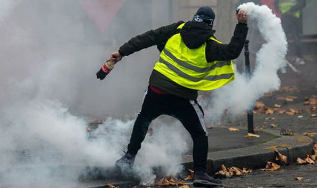 Một người biểu t&igrave;nh n&eacute;m trả lựu đạn hơi cay về ph&iacute;a cảnh s&aacute;t ở Paris h&ocirc;m 1/12.