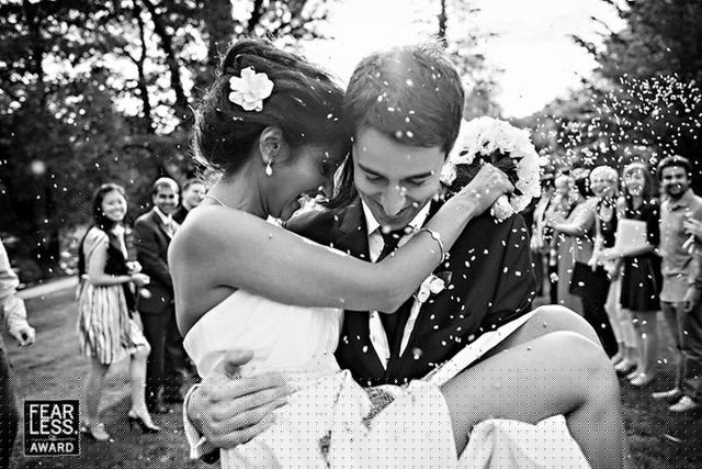 Một chú rể đang bế cô dâu trong đám cưới, rời khỏi những người thân và bạn bè phía sau. Bức ảnh chụp năm 2013 của Samo Rovan.