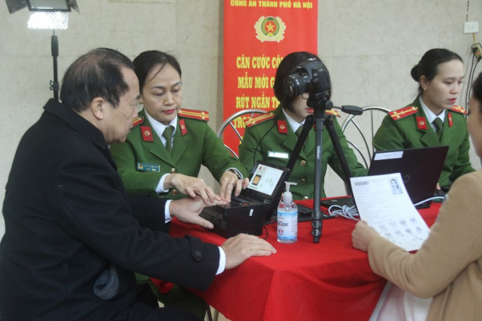 Cán bộ công an thu thập vân tay của người dân đến làm thẻ .